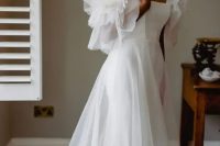 a beautiful off the shoulder A-line wedding dress with ruffles on the sleeves and overskirt plus a train is wow