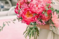 a beautiful pink wedding bouquet of peonies, pincushion peoteas and other flowers and greenery is bold and cool