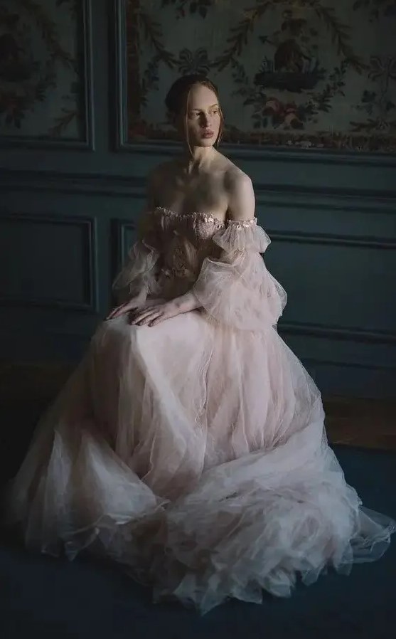 a blush off the shoulder tulle wedding dress with a lace corset and puff sleeves is a very romantic gown