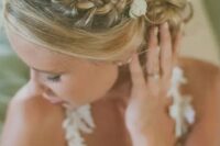 a boho chic braided updo with a curly low bun and some fresh blooms tucked in a beautiful idea for a boho bride