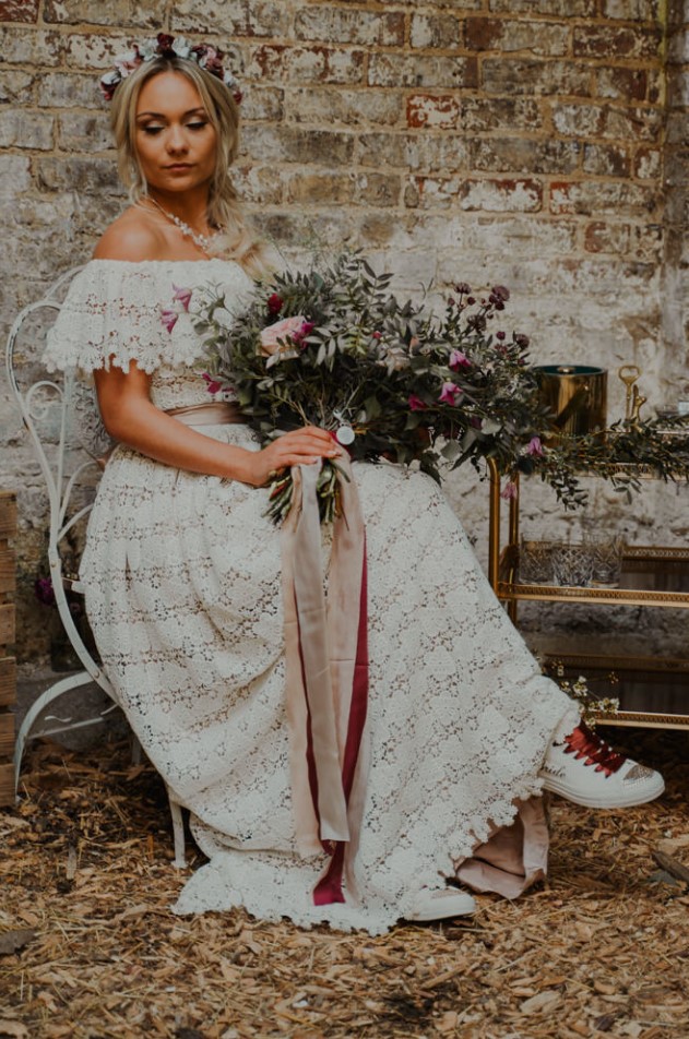 a boho lace off the shoulder wedding dress with a silk sash and a statement necklace plus sneakers