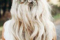a boho wedding half updo with a volume on top, a braided part and waves down plus a pearl hairpiece and baby’s breath