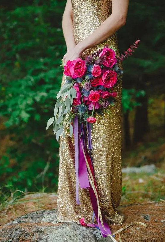a bold jewel-tone wedding bouquet of hot pink blooms, thistles and greenery and long purple and gold ribbons for a bright wedding
