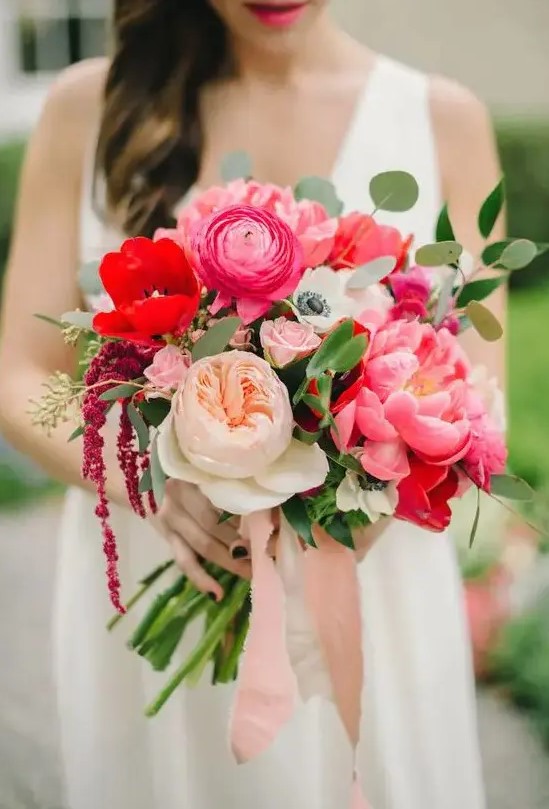 a bold wedding bouquet of pink peonies and ranunculus, neutral peony roses and red anemones and some greenery