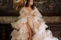 a breathtaking blush off the shoulder tulle wedding dress with puff sleeves and tiers of ruffle and a long train for a refined bride