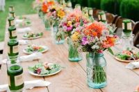 a bright and simple backyard wedding tablescape with bold floral arrangements in bluejars, with bright plates and neutral linens