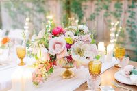 a bright backyard wedding table setting with pink and fuchsia blooms, amber glasses and candles plus neutral linens
