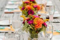 a bright backyard wedding tablescape with an uncovered table and bright menus and napkins, bold floral arrangements and greenery for a summer celebration