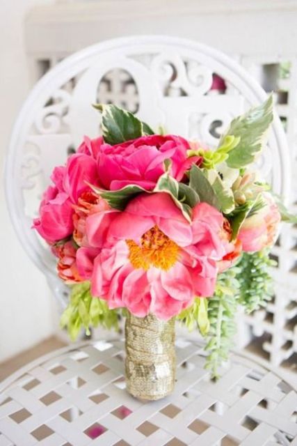 a bright pink peony wedding bouquet with greenery and a gold sequin wrap is a glam and chic wedding idea