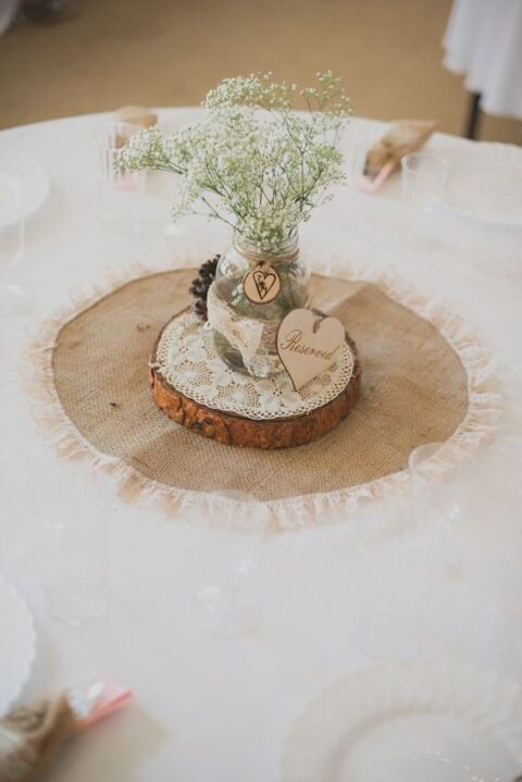 a burlap and lace doily with a wood slice, lace and a jar with burlap and lace and baby’s breath is a cool centerpiece for a rustic wedding