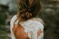 a casual braided and twisted low updo with bangs with some greenery in it is a stylish idea for a casual coastal or beach bride
