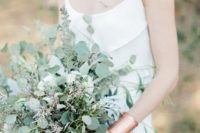 a casual greenery wedding bouquet of eucalyptus and some blooming branches looks very chic