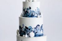 a catchy navy, blue and white wedding cake with brushstrokes and white macarons and meringues for decor