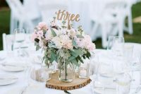 a chic backyard wedding tablescape with neutral linens, pastel blooms and greenery, a wood slice and candles is amazing
