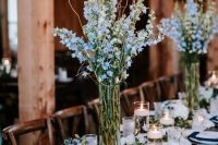 a chic navy and white tablescape with navy napkins, a white table runner, blue floral centerpiece, white floral garlands and candles