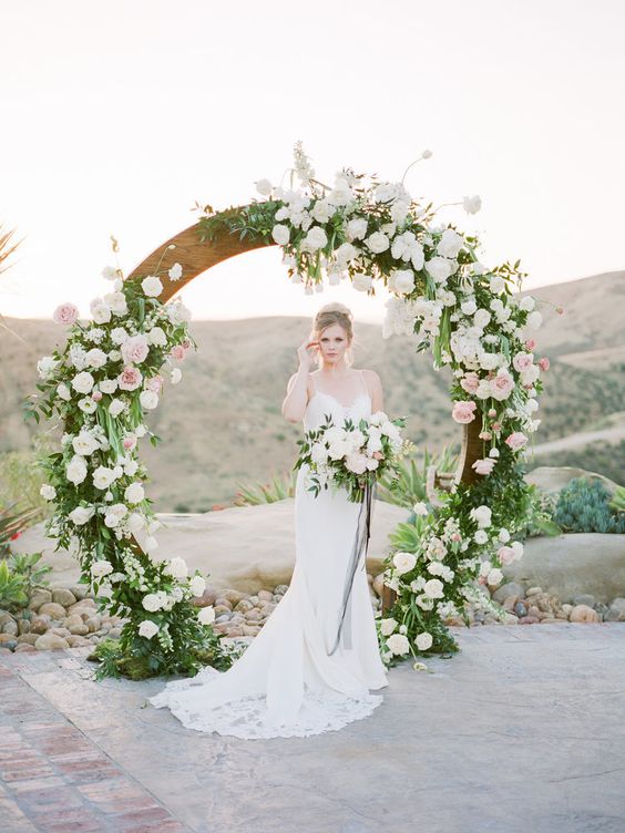 a circle spring wedding arch decorated with lush greenery and white and pink blooms is a trendy idea