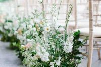 a delicate spring wedding aisle with blooming branches and greenery is a very chic idea for creating a flourishing impression in the space