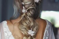 a delicate twisted and loose long ponytail with a mesys volume on top, some waves down, white blooms and beads is chic and ethereal