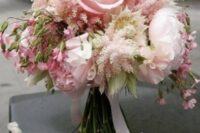 a delicate wedding bouquet with blush peonies and some other blooms plus blush astilbe and white ribbons is very chic
