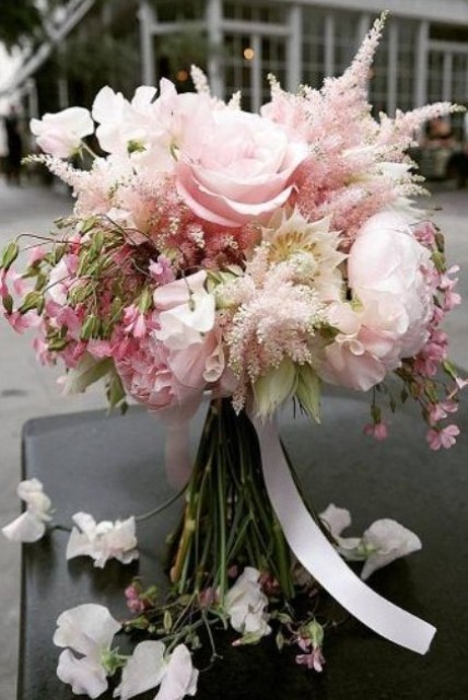 a delicate wedding bouquet with blush peonies and some other blooms plus blush astilbe and white ribbons is very chic