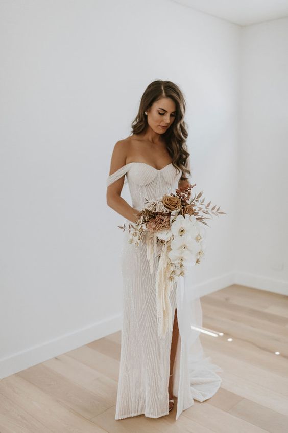 a gorgeous fully embellished sheath off the shoulder wedding dress with a front slit and a small train is lovely