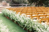 a gorgeous rustic wedding aisle with super lush greenery and white florals in planters is a fantastic idea to support that flourishing feel of spring