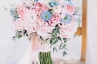 a gorgeous wedding bouquet of pink roses and peonies and some blue blooms and long blush ribbons is amazing