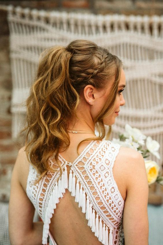 A high wavy ponytail with a braided halo, a bump on top and face framing locks is a gorgeous boho wedding hairstyle