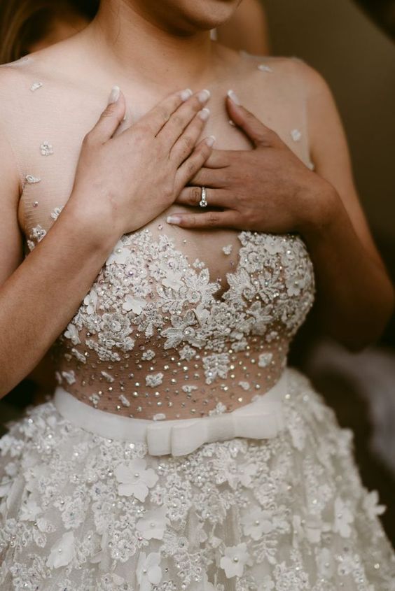 a jaw-dropping lace applique and rhinestone wedding dress with an illusion neckline and no sleeves is very girlish and sexy