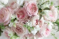 a light pink and white wedding bouquet with greenery and white fillers is a delicate and subtle touch of color to the bridal look