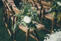 a lovely and fresh spring wedding aisle with white petals on the ground, with white ranunculus and greenery on the chairs