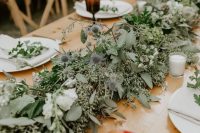 a lovely backyard wedding tablescape with a lush eucalyptus and thistle runner, candles and white linens is a fresh idea