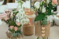a lovely cluster wedding centerpiece of jars wrapped with burlap, with wooden buttons, lace and white and pink blooms