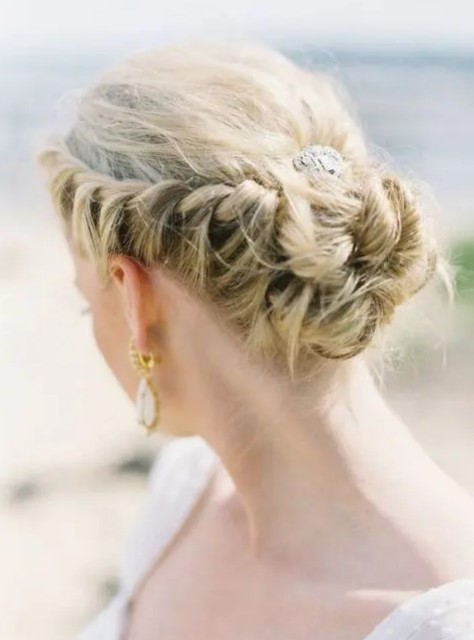 a low bun with two side braids farming the head and a rhinestone plus a messy top for a summer wedding