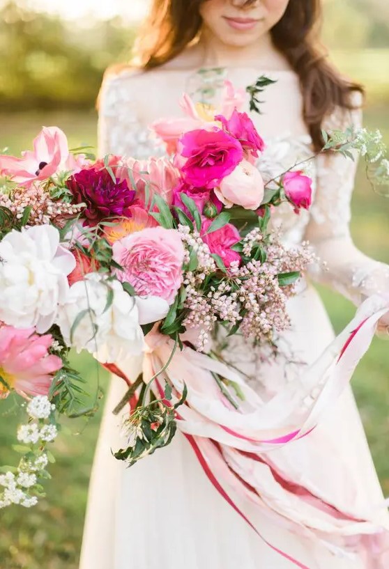 a lush and dimensional pink wedding bouquet with white, light pink and hot pink blooms, berries and greenery plus ribbons