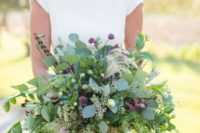 a lush summer wedding bouquet with lots of greenery, small pink blooms and feathers is a bold idea