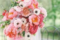 a lush wedding bouquet with pink peonies, ranunculus, anemones, some greenery is a stylish idea for a pink wedding