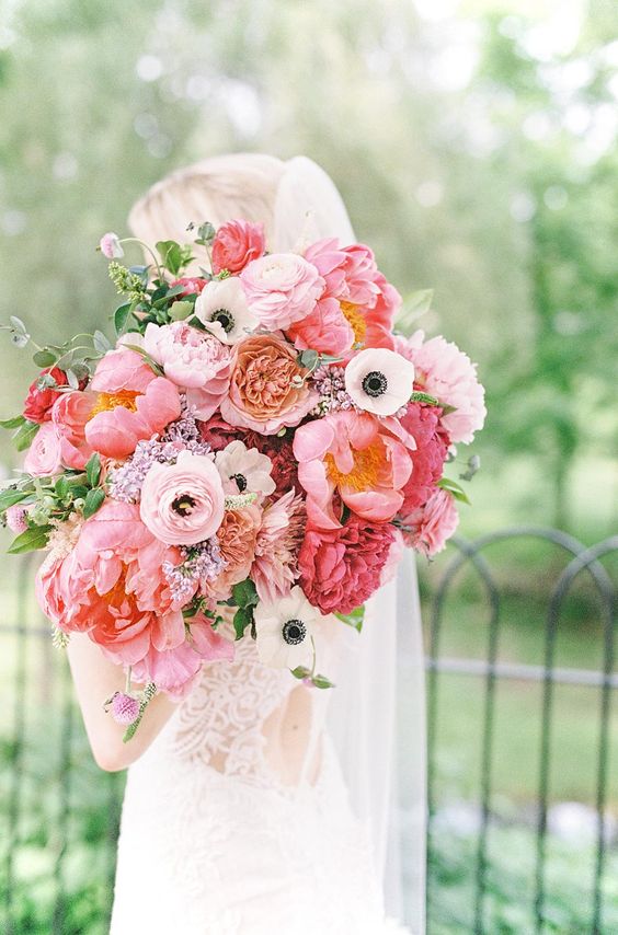a lush wedding bouquet with pink peonies, ranunculus, anemones, some greenery is a stylish idea for a pink wedding