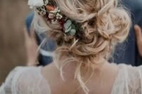 a messy and loose wedding low updo with waves and locks down and with a floral accent – neutral and blush blooms and greenery
