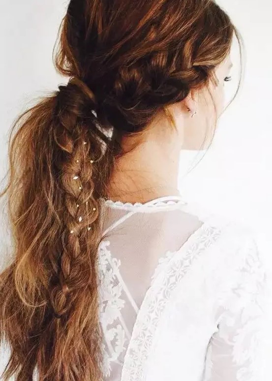 a messy textural ponytail with a bump and a side braid with tin flowers in for a boho bride