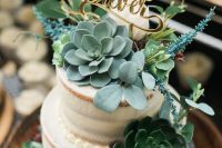 a naked wedding cake decorated with sugar beads, with succulents, greenery and blooms, with a gold calligraphy topper is amazing