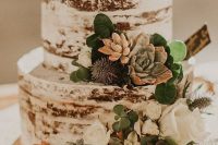 a naked wedding cake with greenery, succulents, thistles and white blooms for a rustic wedding