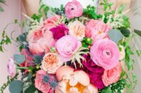 a pink wedding bouquet with bright, coral and peachy pink blooms, greenery, thistles and berries is a bold and catchy idea for a summer wedding