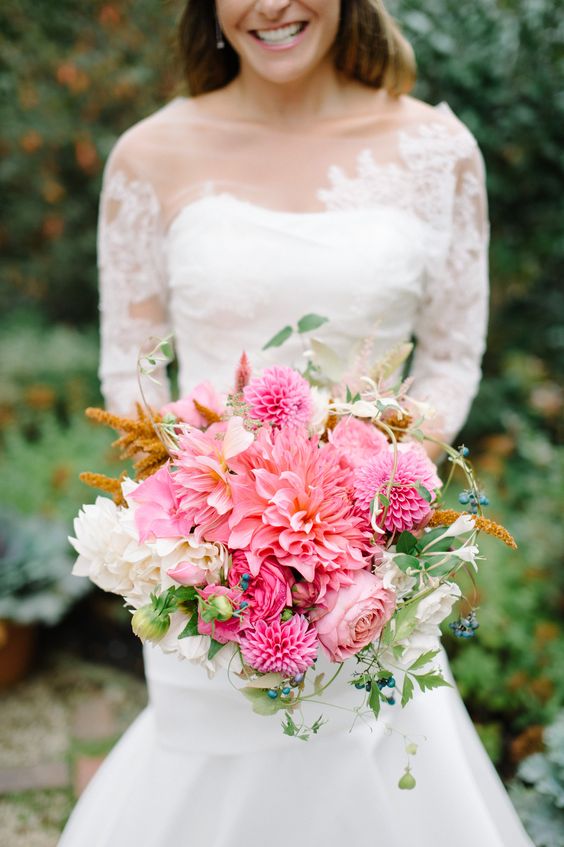 a pink wedding bouquet with dahlias, roses, white dahlias and some greenery and berries for a spring or summer wedding