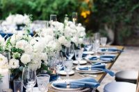 a refined navy and white wedding table setting with a navy table runner, white floral centerpieces, navy napkins and silver