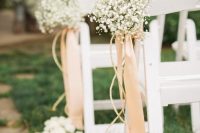 a refined vintage wedding aisle with white baby’s breath arrangements with blush ribbons and white petals on the ground is chic