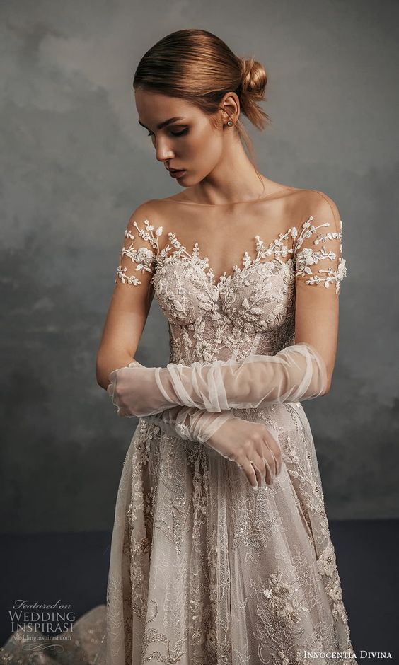 a romantic blush lace applique wedding dress with an illusion neckline, cap sleeves and floral lace applique all over the dress