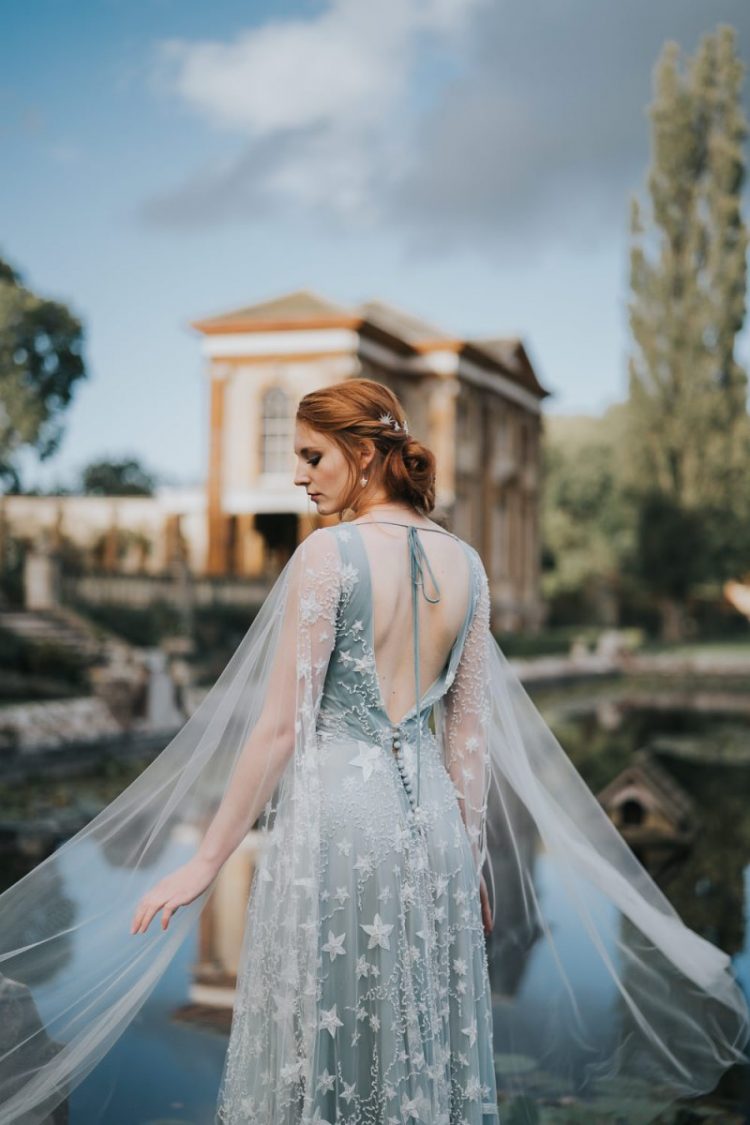 a romantic celestial pale blue wedding dress with star embroidery, an open back and a capelet