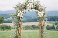 a romantic spring wedding arch done with greenery and neutral and blush blooms looks cool