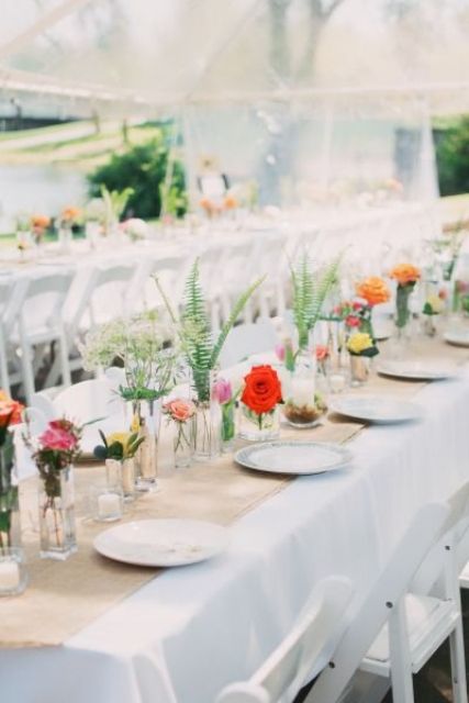 a rustic backyard wedding tablescape with neutral linens, a burlap runner, bright cluster floral centerpieces and printed plates is a cool idea